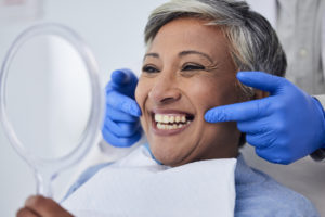 The image shows a woman smiling at a dentist appointment to show the benefits of cosmetic dentistry