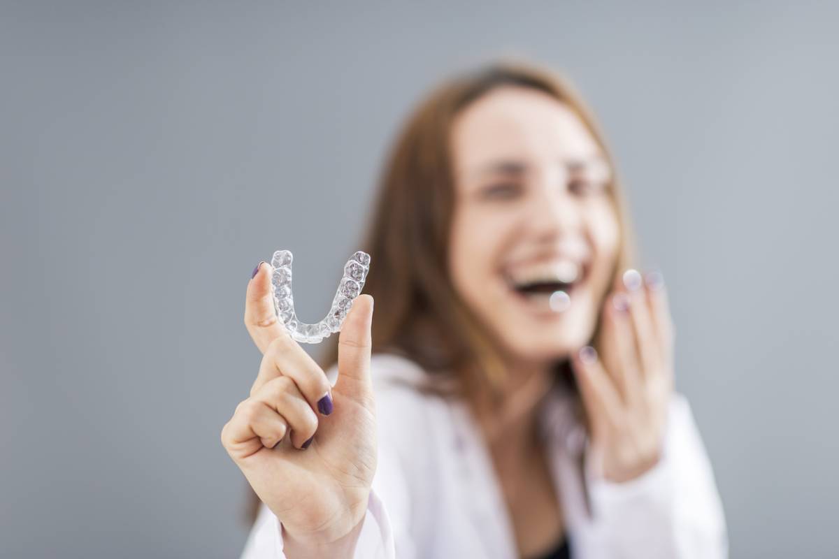 Woman smiling with Invisalign in her hands