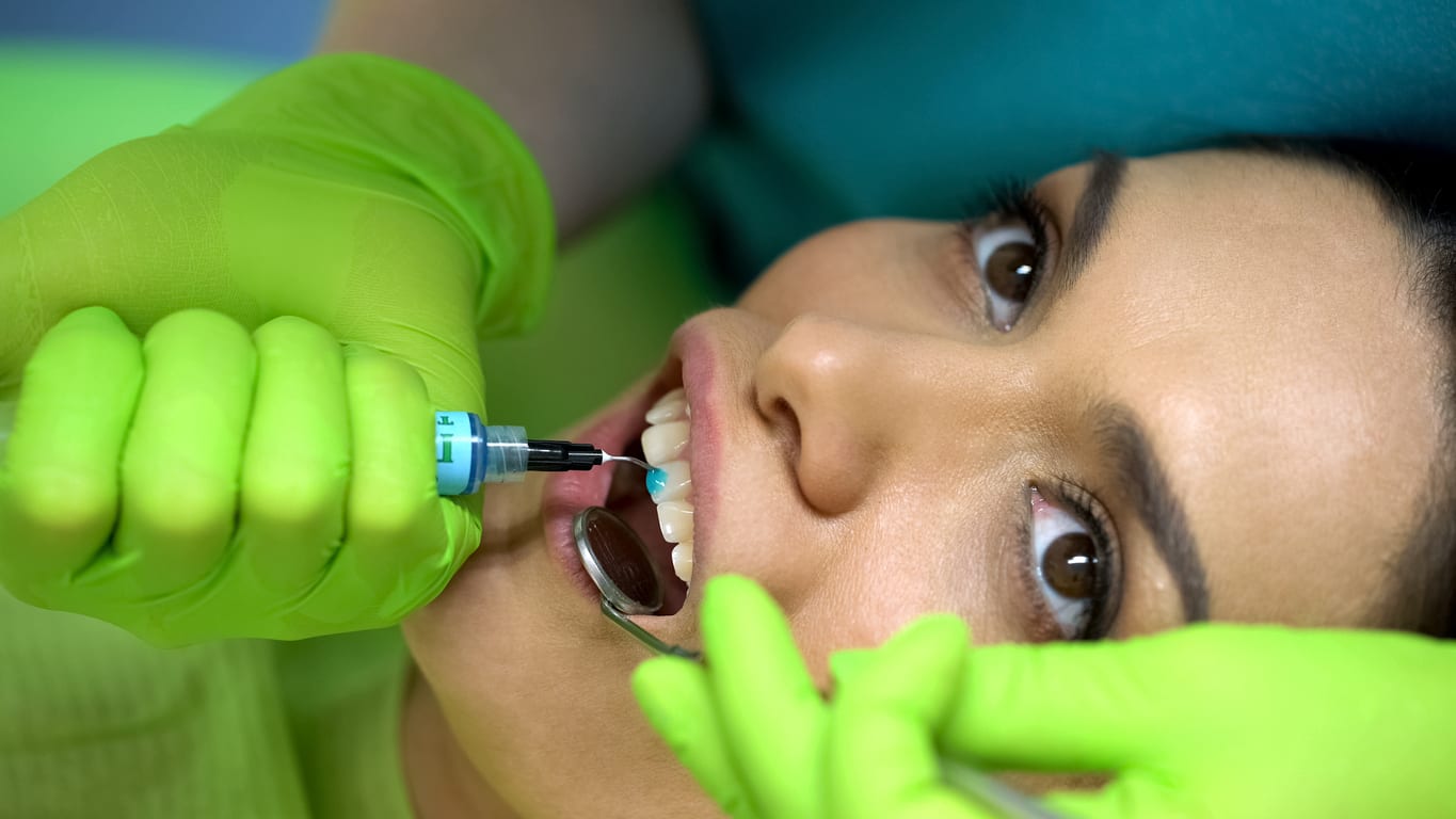 Stomatologist applying blue gel on tooth, cosmetic dentistry stock photo