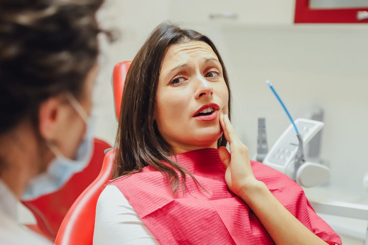 Close-up portrait of a sad young girl with a painful tooth, a doctor in office chairs, an isolated dentist office stock photo