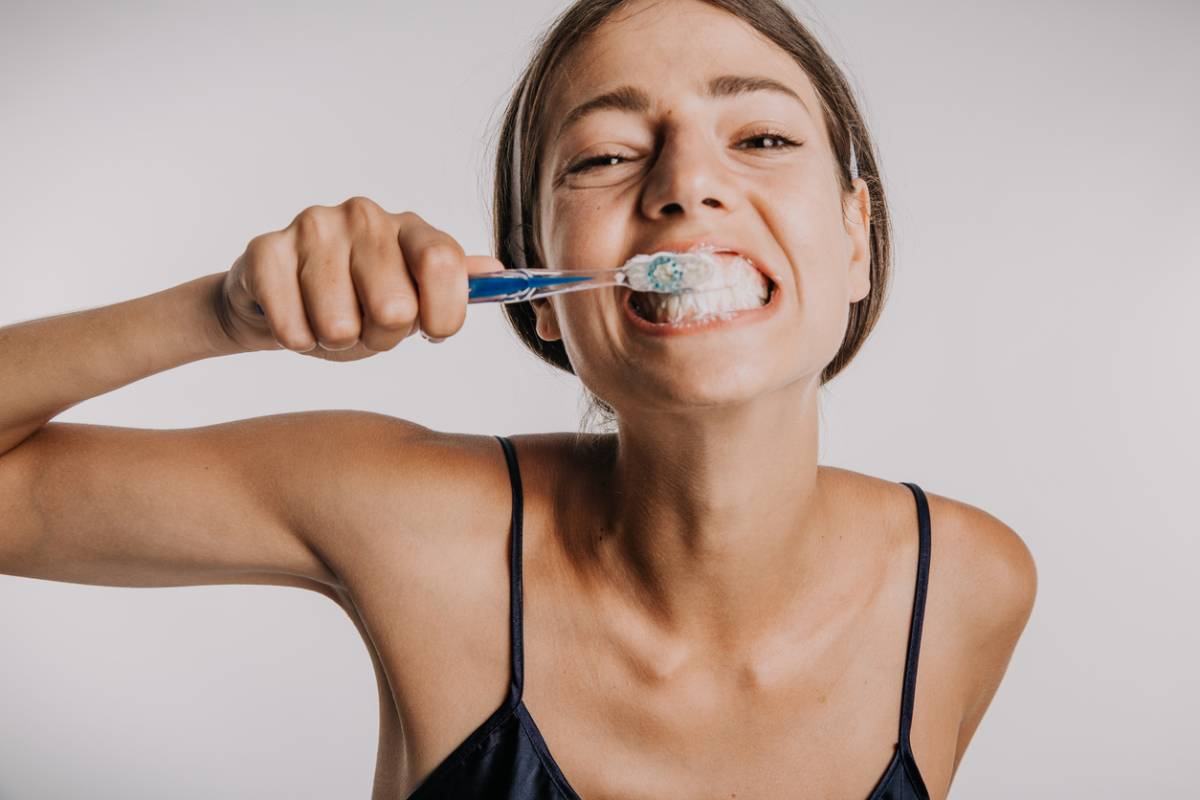 Woman brushing her teeth to avoid dental plaque.